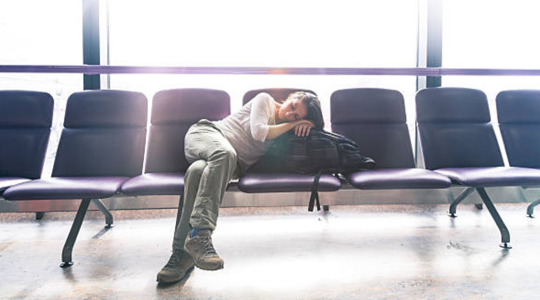Woman in airport sleeping from jetlag 